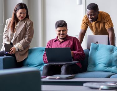 Three students gathered around a computer 