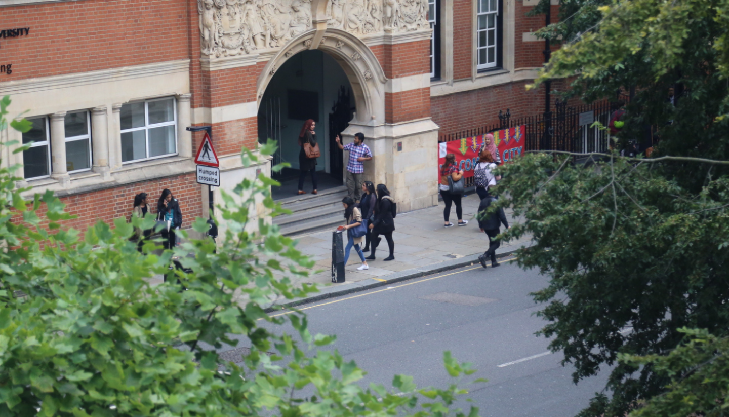 Several people walking by college building